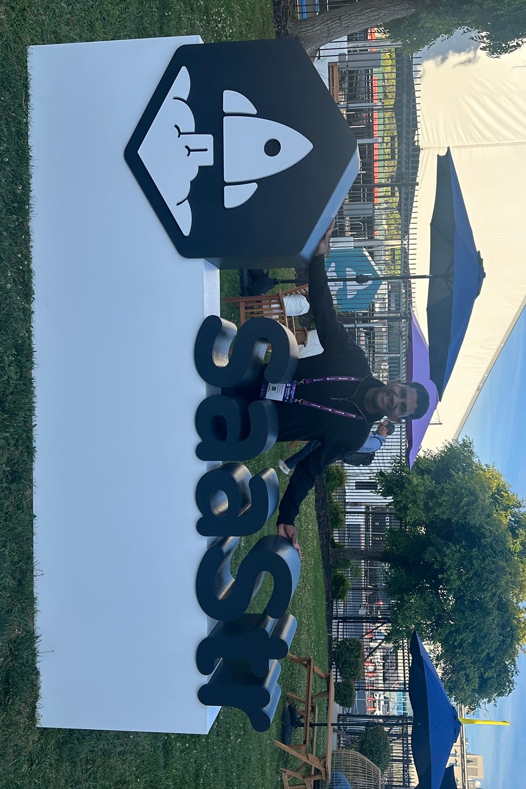 Deepak Gupta standing beside the SaaStr rocket logo and letter sign on the lawn outside the venue
